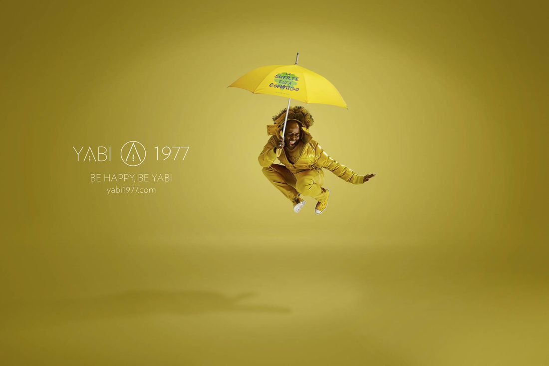 YABI 1977 — hombre saltando con paraguas amarillo: la suerte está conmigo
