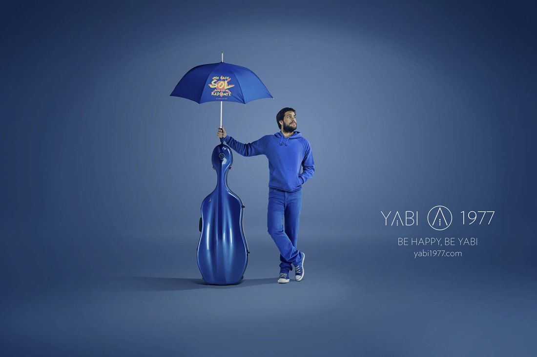 YABI 1977 en azul: chelista con paraguas que dice no hace sol pero estoy radiante