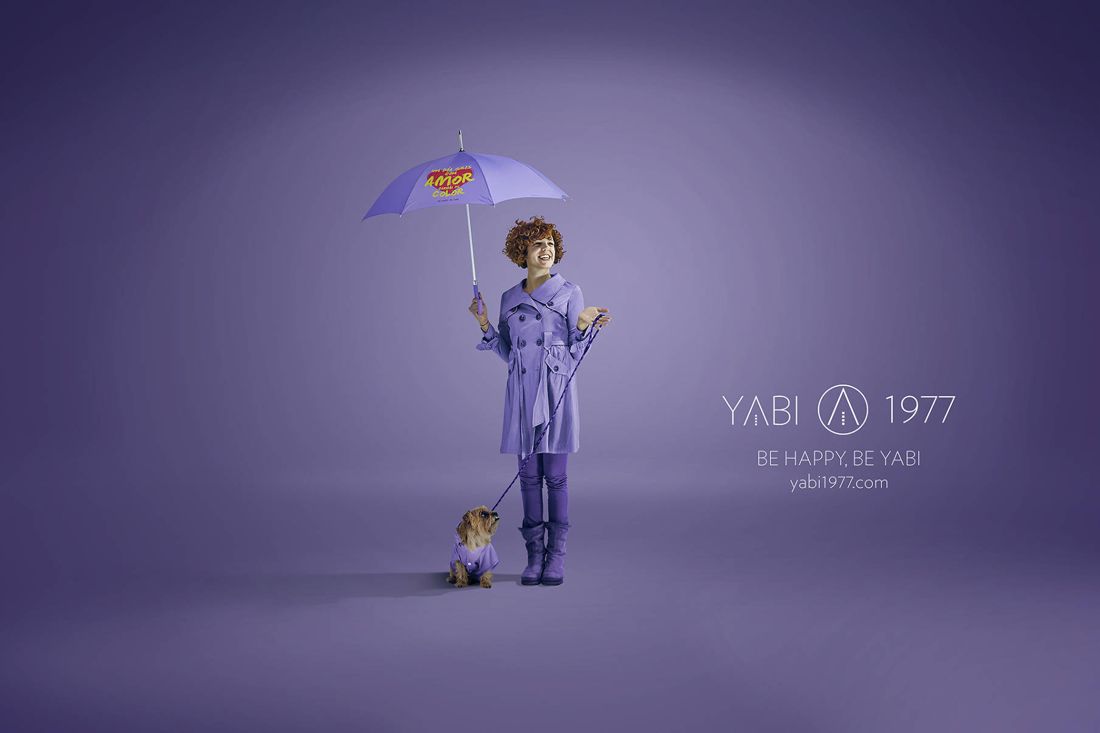 YABI 1977 en lila: mujer con perro y paraguas que dice un día gris con amor cambia de color